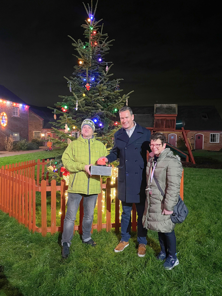 Gareth Griffiths at the Save the Family Christmas light switch on standing in front of the tree with 2 attendees