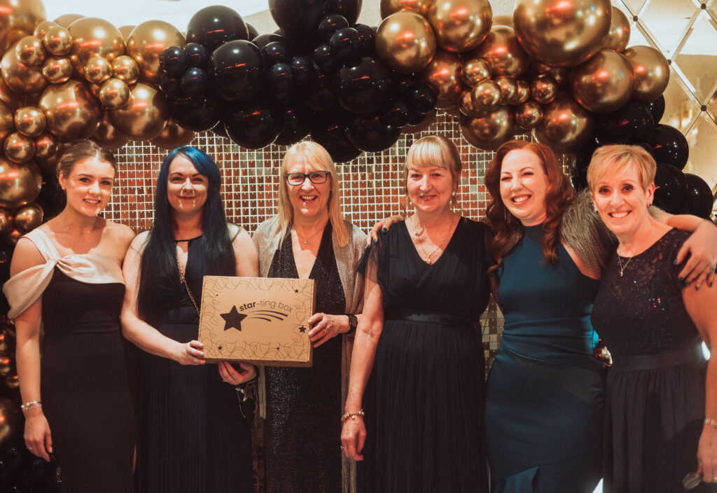 Grace Parry and the Starting Box team at the charity ball standing in front of balloons and a sequin wall