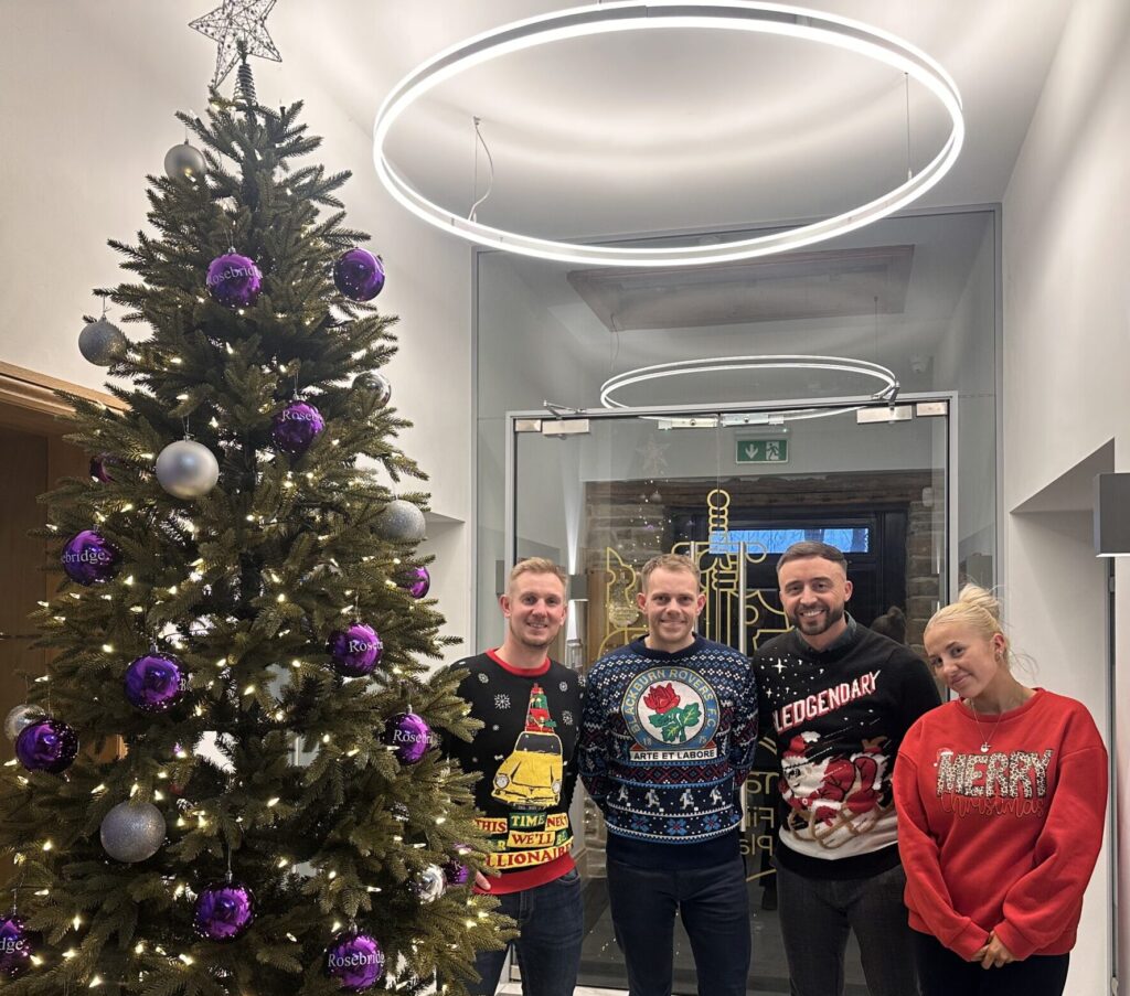 Pro Sport 2025 team wearing christmas jumpers in front of a christmas tree